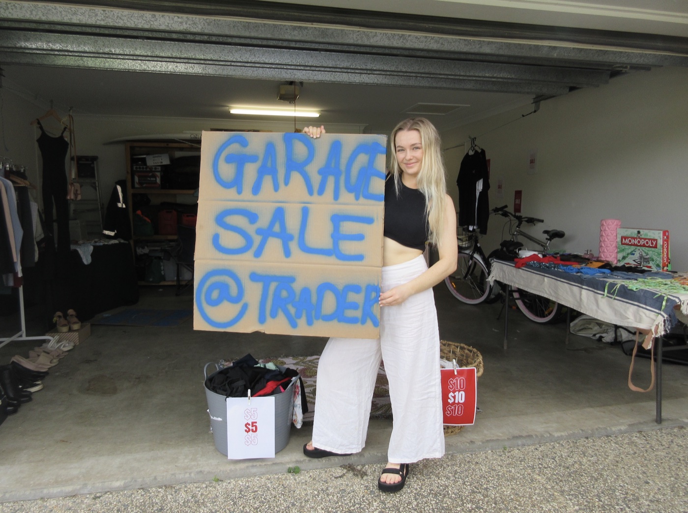 Zoe holding a hand-painted "Garage Sale" sign