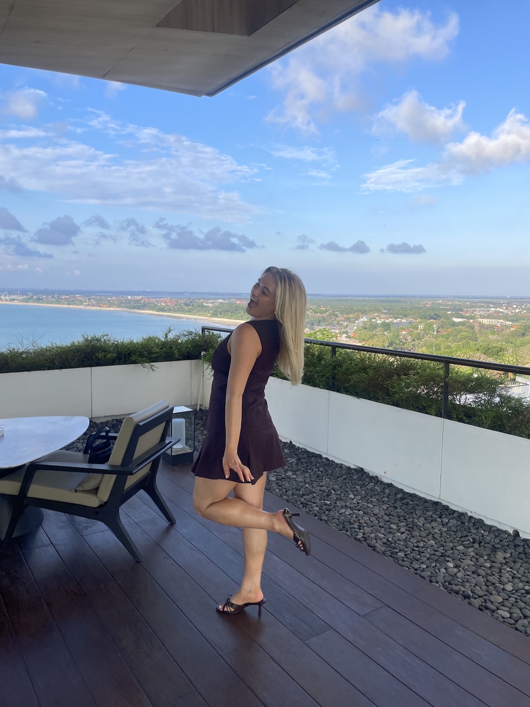 Zoe laughing on a rooftop balcony overlooking the coast