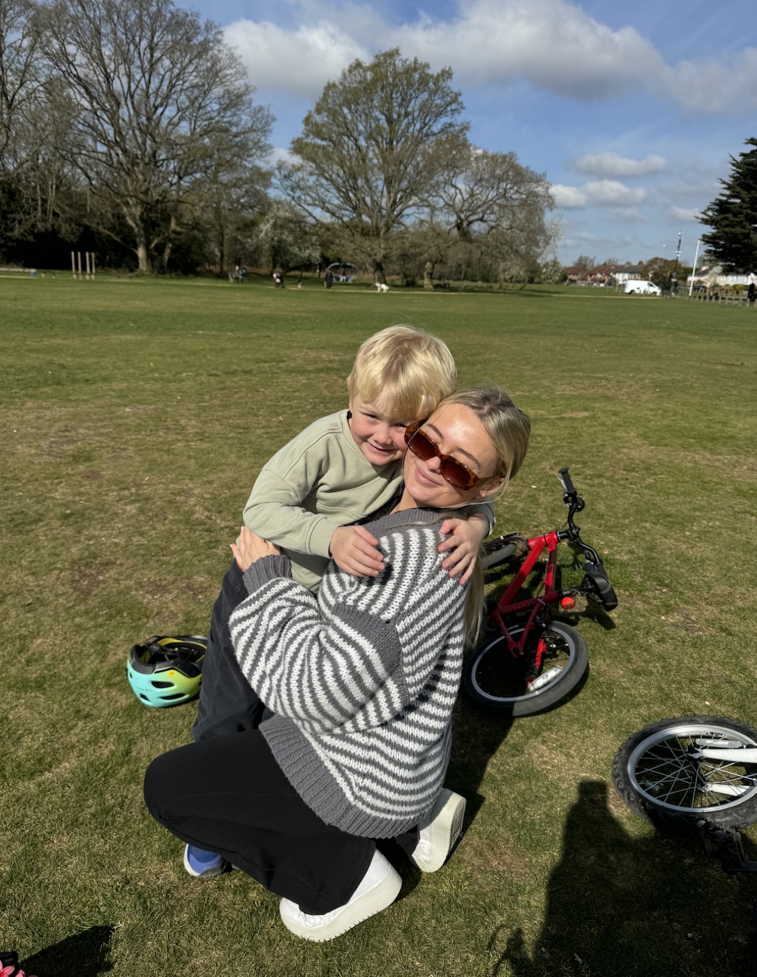 Zoe hugging a young boy in a park, bikes in the background