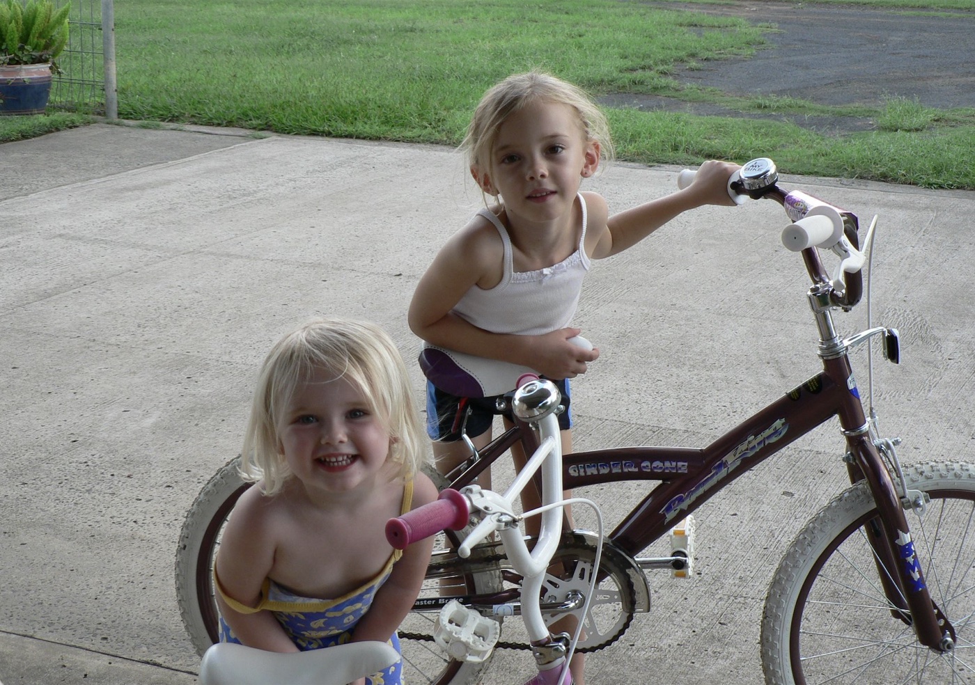 Zoe as a young girl with a sibling and a bike in the driveway
