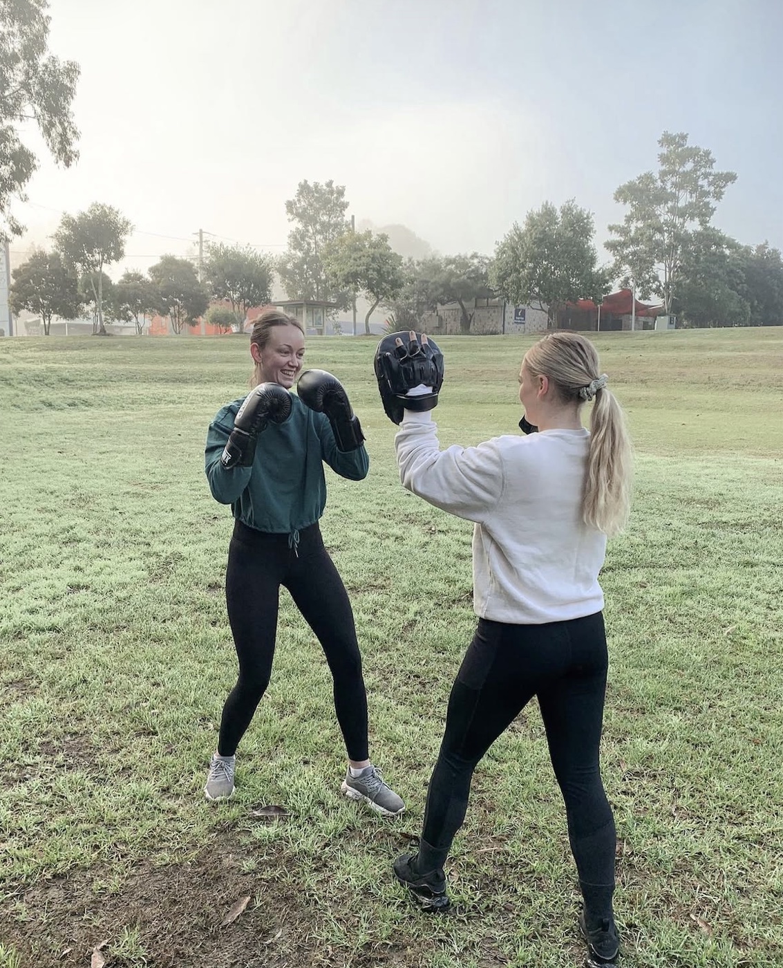 Zoe holding boxing pads for a client outdoors